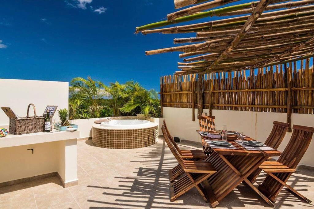 a patio with a table and chairs and a hot tub at Aldea Zama Penthouse with Private Rooftop in Tulum