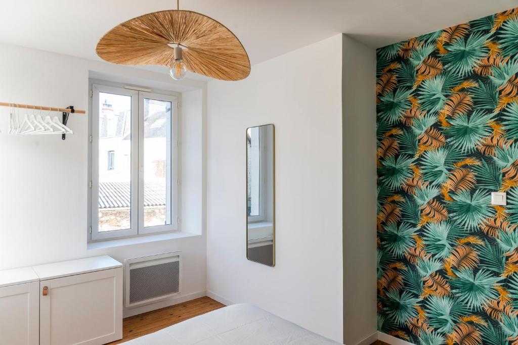 a bedroom with a tropical wallpaper on the wall at Jolie maison proche centre-ville et plages in Granville