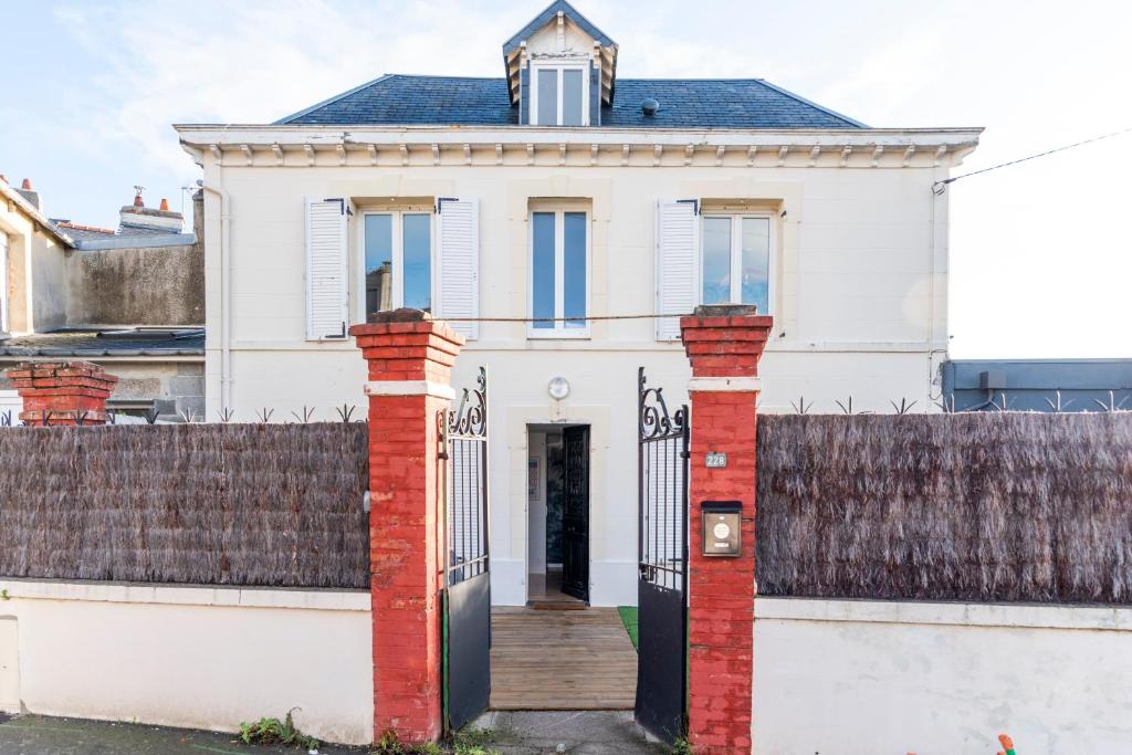 una casa blanca con una puerta y una valla en Jolie maison proche centre-ville et plages en Granville