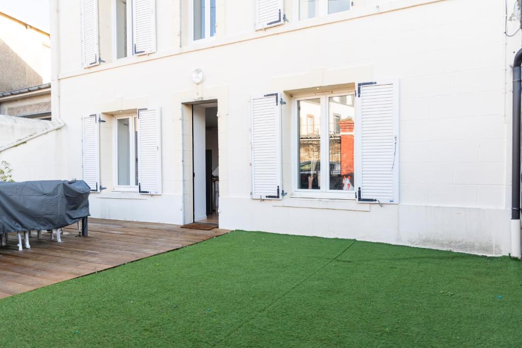 a patio with a green lawn in front of a building at Jolie maison proche centre-ville et plages in Granville
