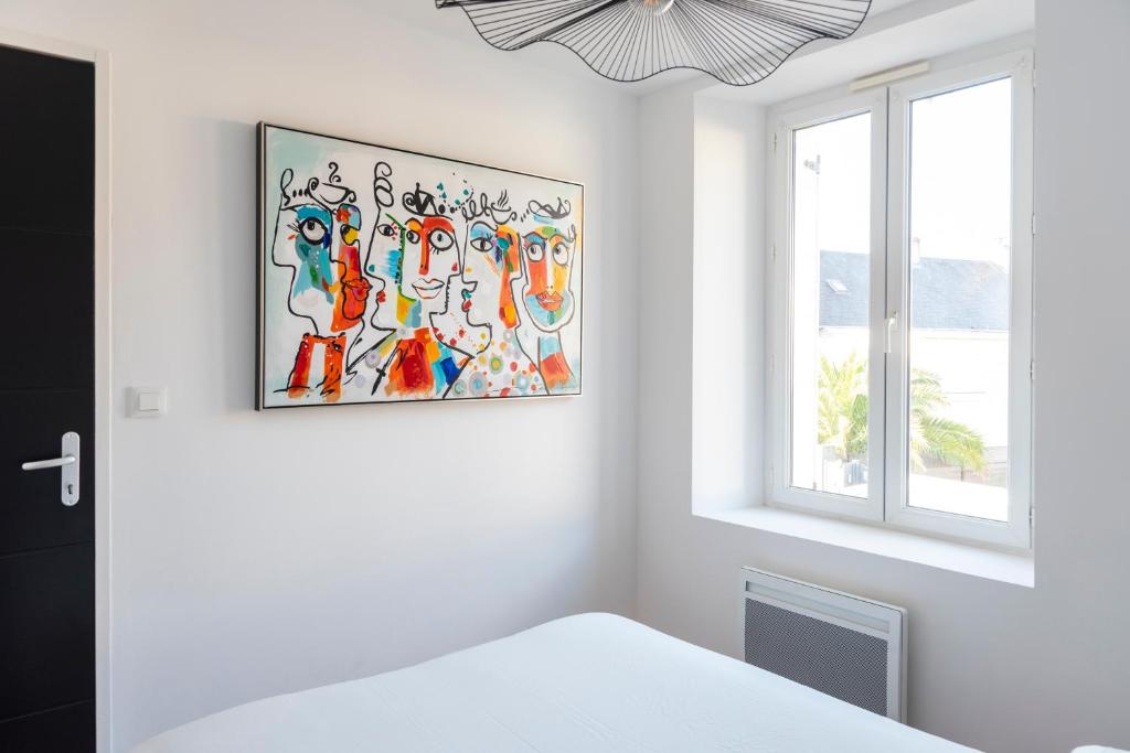 a white bedroom with a painting on the wall at Jolie maison proche centre-ville et plages in Granville
