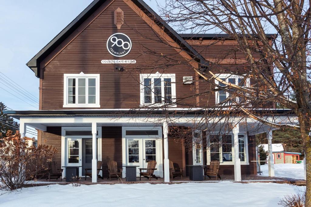 un bâtiment brun avec un panneau dans la neige dans l'établissement Le 900 Tremblant Inn Café and Bistro, à Mont-Tremblant