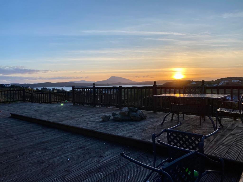 a sunset on a deck with a table and chairs at Torrans Cottage in Downings