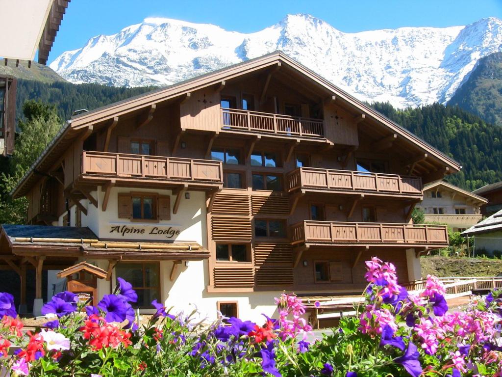 un grand bâtiment en bois avec des montagnes en arrière-plan dans l'établissement Alpine Lodge 5, aux Contamines-Montjoie