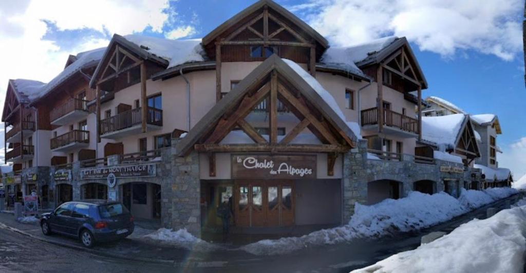 a large building with a car parked in front of it at Bel appartement lumineux au pied des pistes in Valmeinier