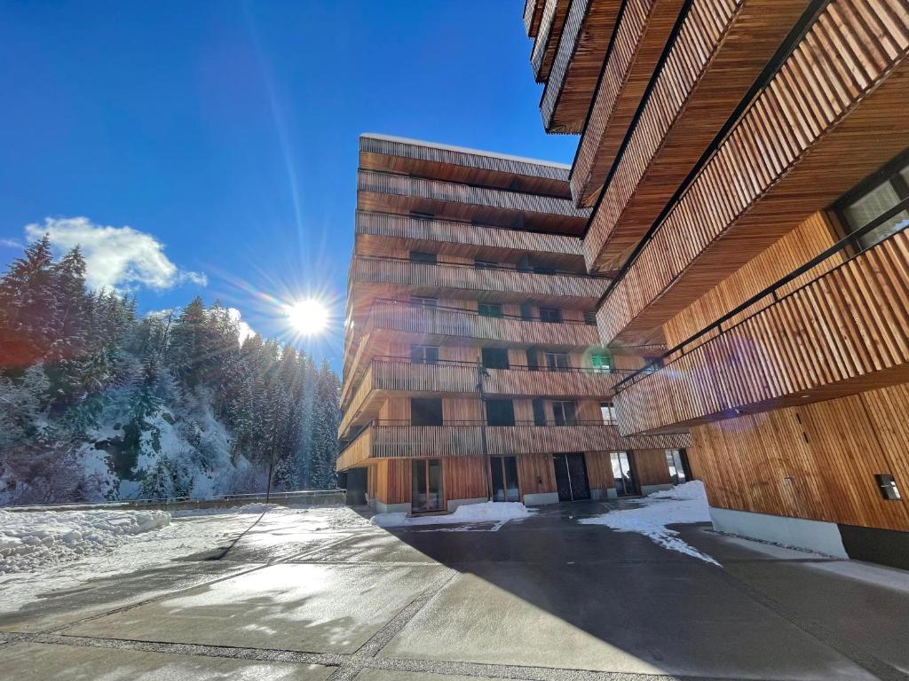 ein hohes Gebäude mit der Sonne am Himmel in der Unterkunft Selva Mountain Apartment in Flims