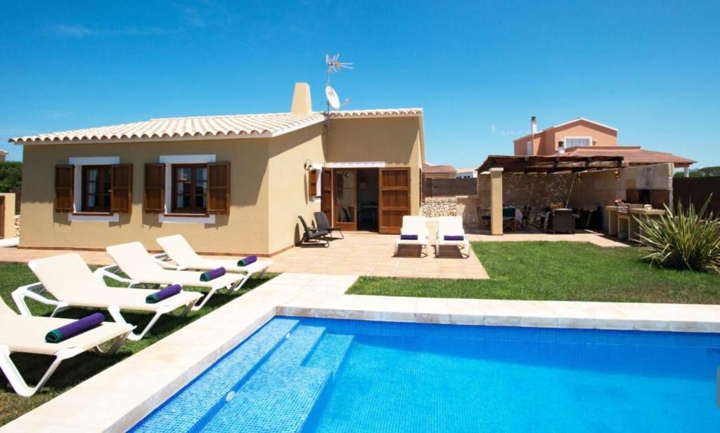 a villa with a swimming pool in front of a house at Villas Sa Ferradura in Cala en Blanes