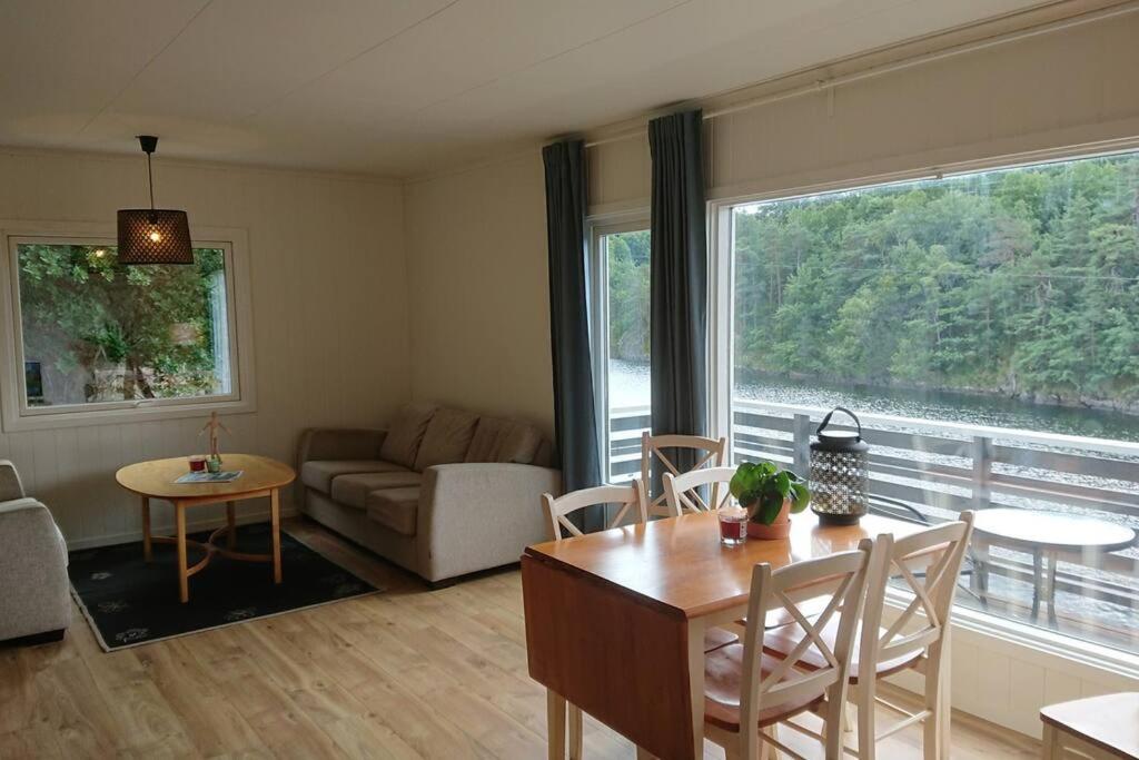 sala de estar con mesa, sillas y ventana grande en Rolig og idyllisk, men sentralt i Kristiansand, en Kristiansand