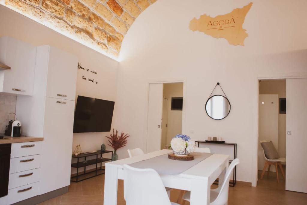 a white dining room with a white table and chairs at Agorà Home in Terrasini