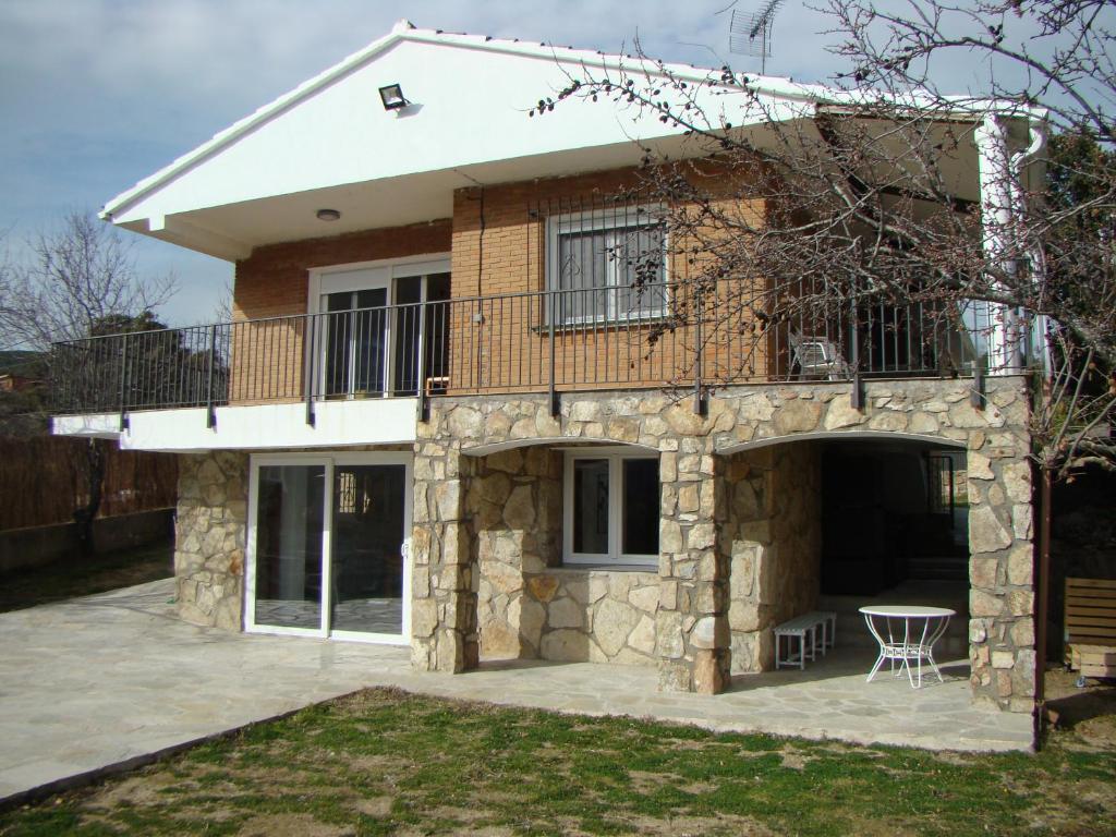 une maison avec un balcon au-dessus dans l'établissement Chalet con piscina y BBQ para 10 personas, à San Martín de Valdeiglesias