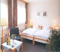 a bedroom with a bed and a table and a chair at Hotel & Freizeitpark Am Lärchenberg in Schirgiswalde