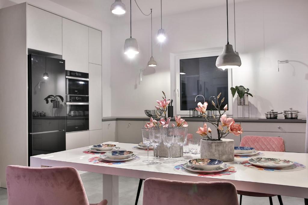 a white kitchen with a table with plates and flowers on it at Apartamenty przy Bulwarach in Rabka