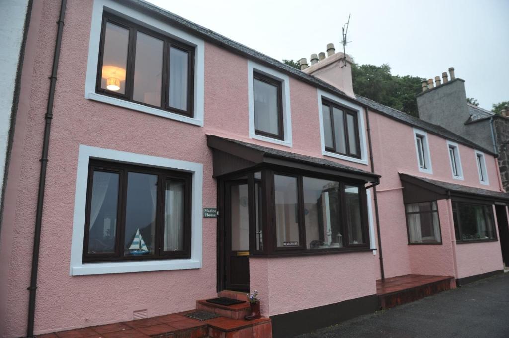 a pink house with black windows on a street at Marine House Holiday Home in Portree