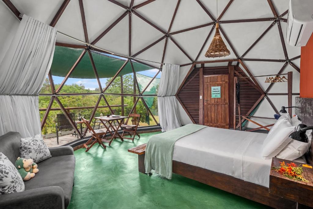 um quarto com uma cama num quarto com janelas de vidro em Glamping Serra da Canastra - Casinha de Hortelã - Domo Embaúba em Delfinópolis