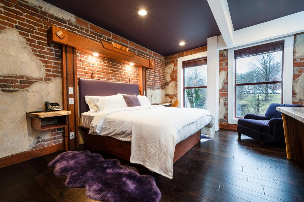 a bedroom with a bed and a brick wall at The Horton Hotel in Boone
