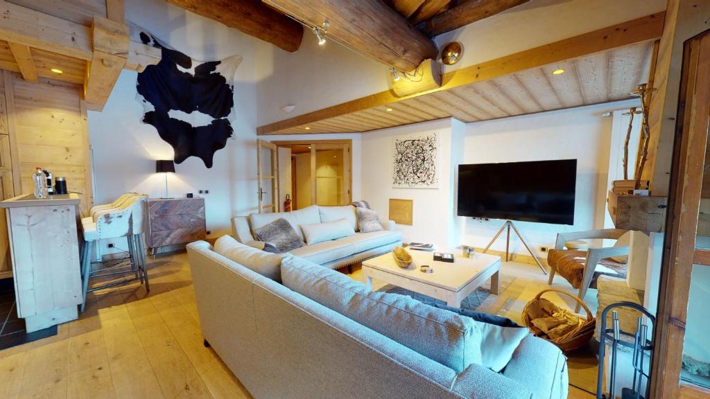 ein Wohnzimmer mit einem Sofa und einem TV in der Unterkunft Résidence Le Lys Martagon in Val dʼIsère