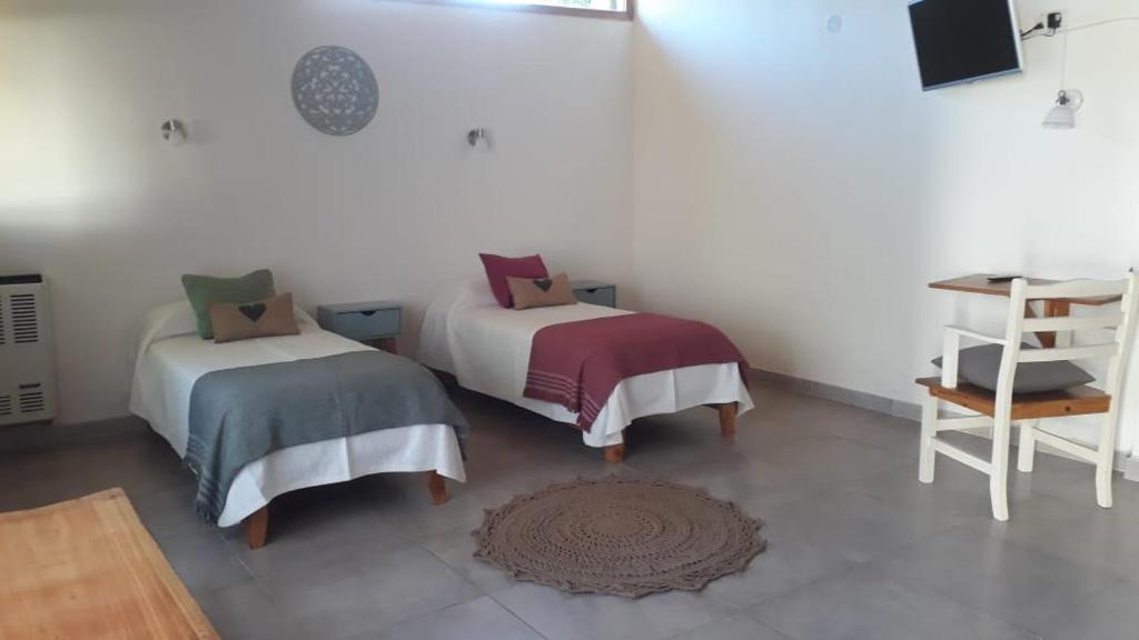 a room with two beds and a table and a desk at Arboleda Monoambiente in El Hoyo