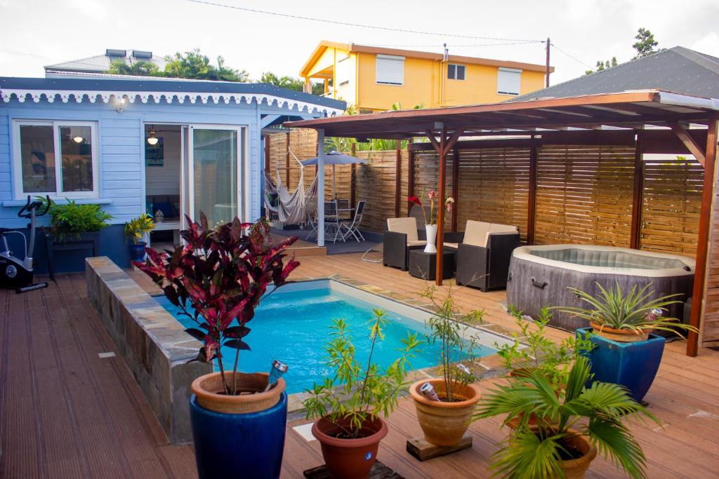 een achtertuin met een zwembad en potplanten bij Les Bougainvilliers Tropicaux in Sans Pareil