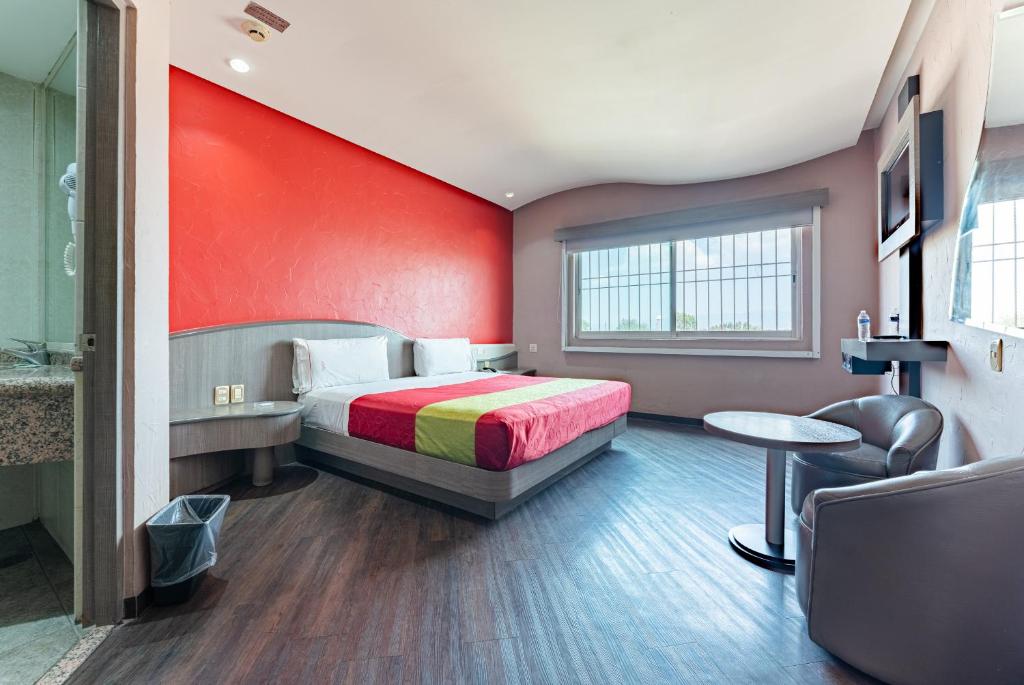 1 dormitorio con cama y pared roja en Hotel y Villas Vento, en Ciudad de México