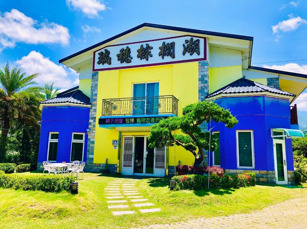 uma casa amarela e azul com um quintal em Ruisui Palm Lakes B&B em Ruisui