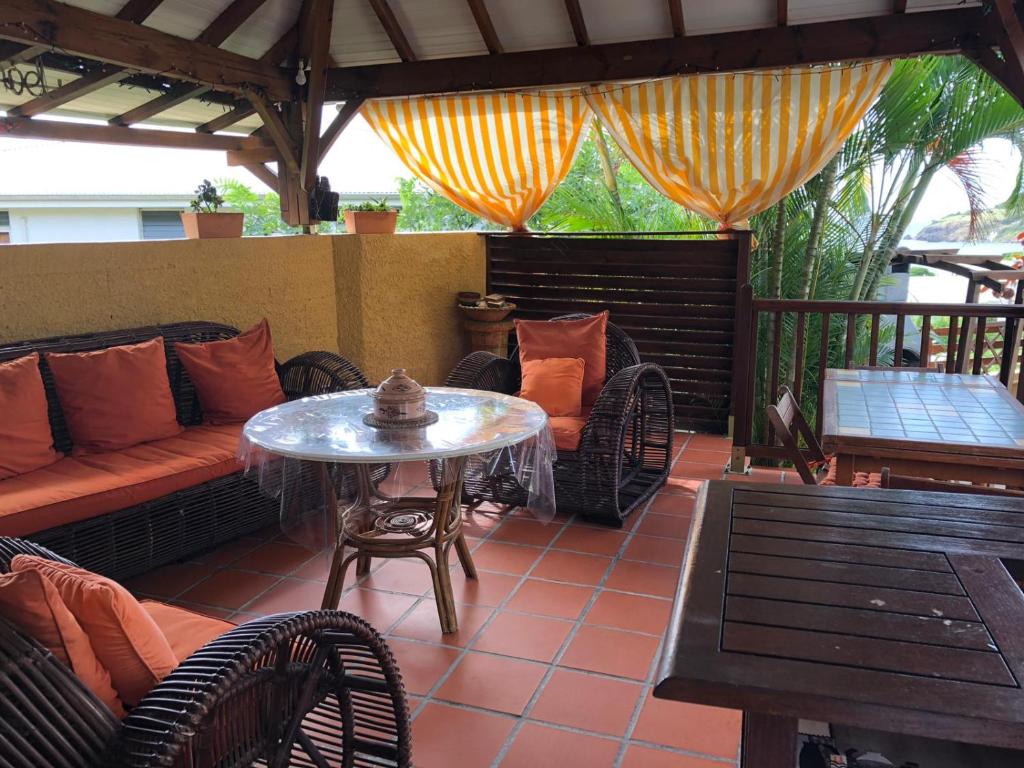 a patio with a couch and a table and chairs at Kay Ghislaine in Les Anses-dʼArlets