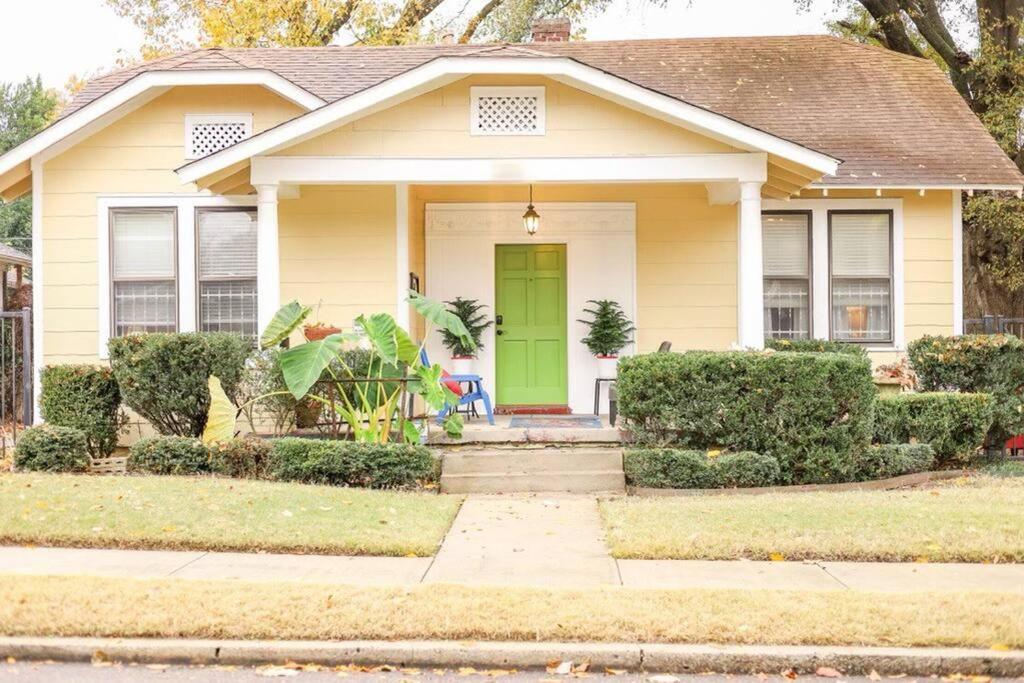 una casa amarilla con una puerta verde en J Birds’ Bungalow in the heart of Midtown en Memphis