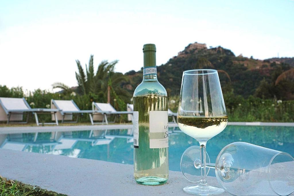 una botella de vino y una copa junto a la piscina en Holiday home, Castiglione di Sicilia, en Castiglione di Sicilia