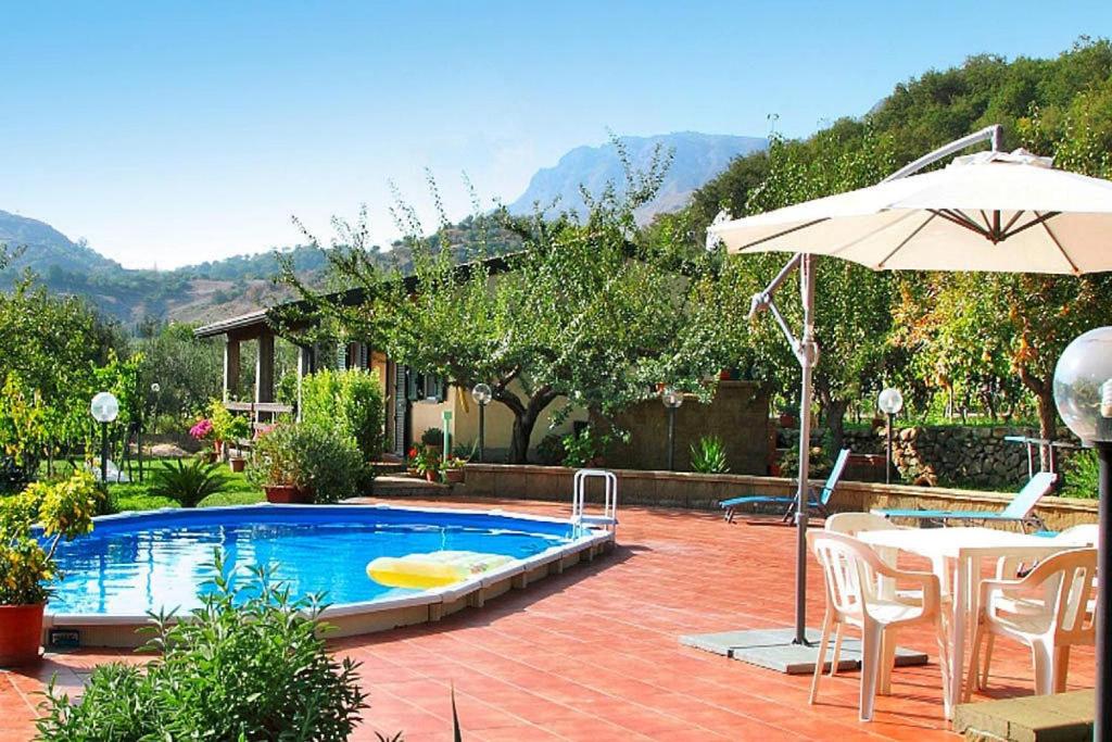 a swimming pool with a table and an umbrella at Holiday home, Francavilla di Sicilia in Francavilla di Sicilia