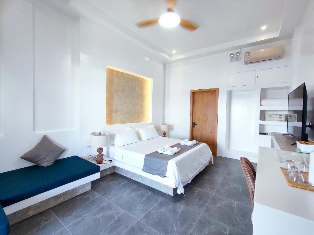 Bohol Coastal View Hotel في Taiwala: غرفة نوم بسرير واريكة وتلفزيون