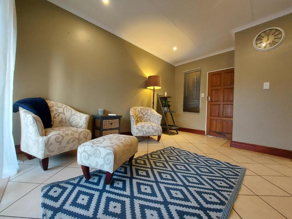 a living room with two chairs and a rug at Private Apartment for business and leisure Pretoria East in Pretoria