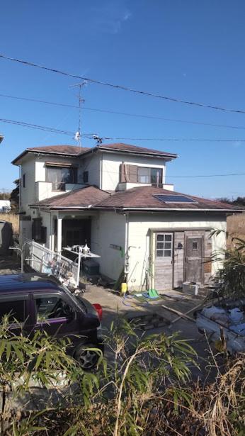una casa blanca con un coche aparcado delante de ella en 川っぺり　大出 en Kujukuri