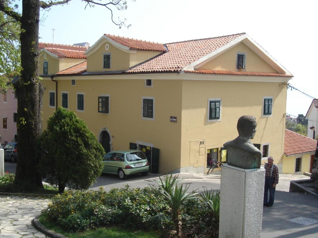um edifício amarelo com um carro estacionado em frente em Apartments Villa Kastav em Kastav