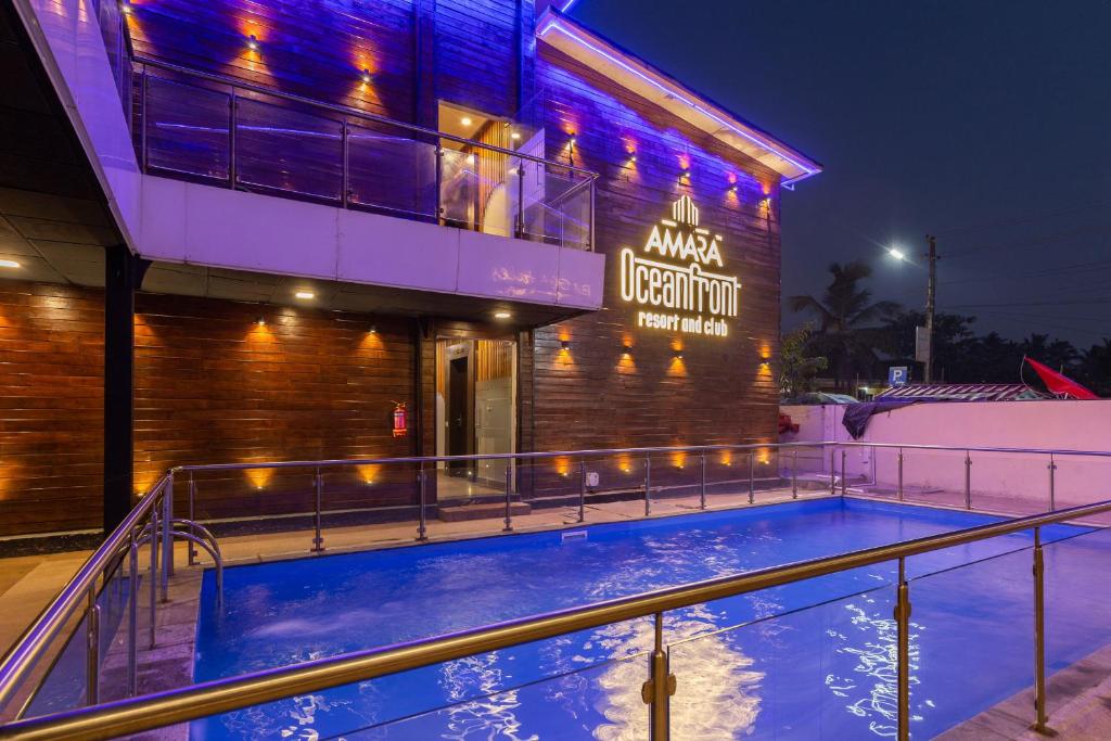 a swimming pool in front of a building at night at Amara Oceanfront Resort & Club Baga in Baga