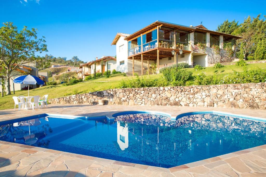 a villa with a swimming pool in front of a house at Pousada Morro Verde in Águas de Lindoia
