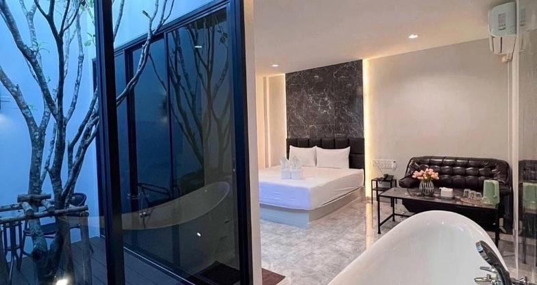 un bagno con un letto e una stanza con uno specchio di VEVILLA a Bangkok