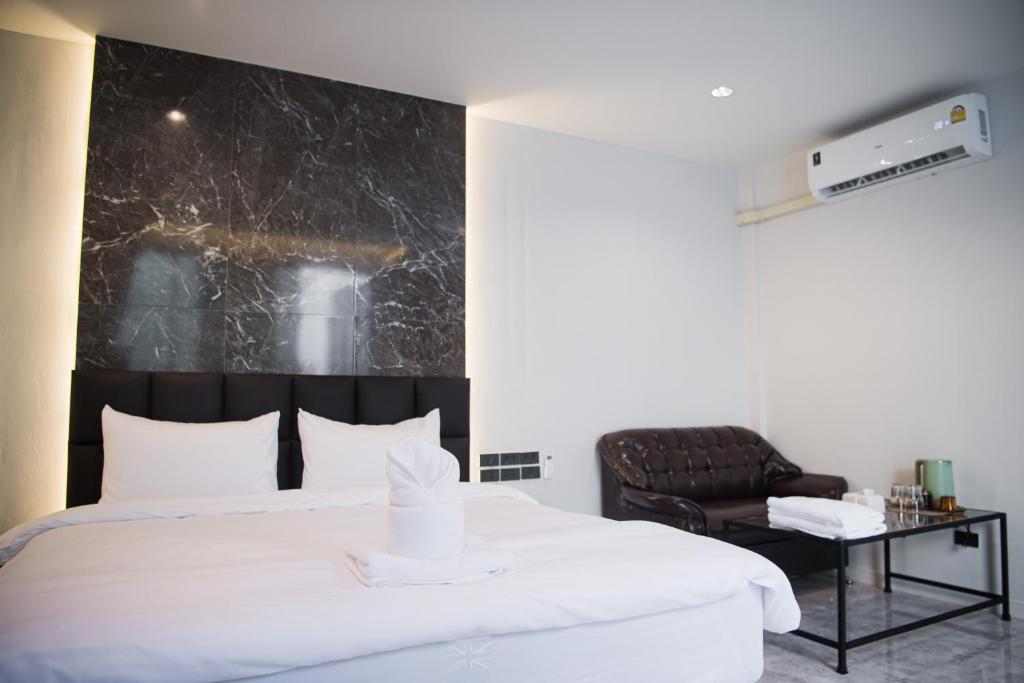 a bedroom with a large white bed and a chair at VEVILLA in Bangkok