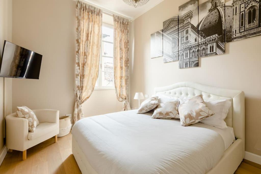 ein Schlafzimmer mit einem weißen Bett und einem Stuhl in der Unterkunft Duomo Luxury Home with view in Florenz