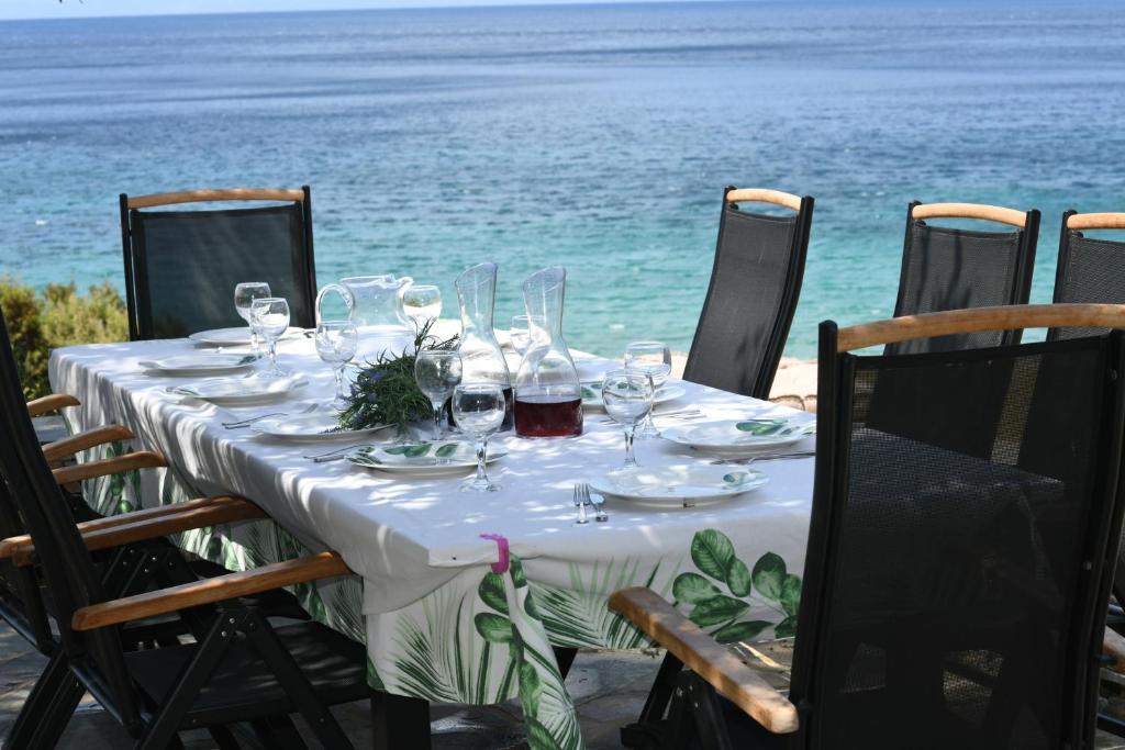 a table with wine glasses and the ocean in the background at Sun Senses - villa with private beach in Ayía Marína