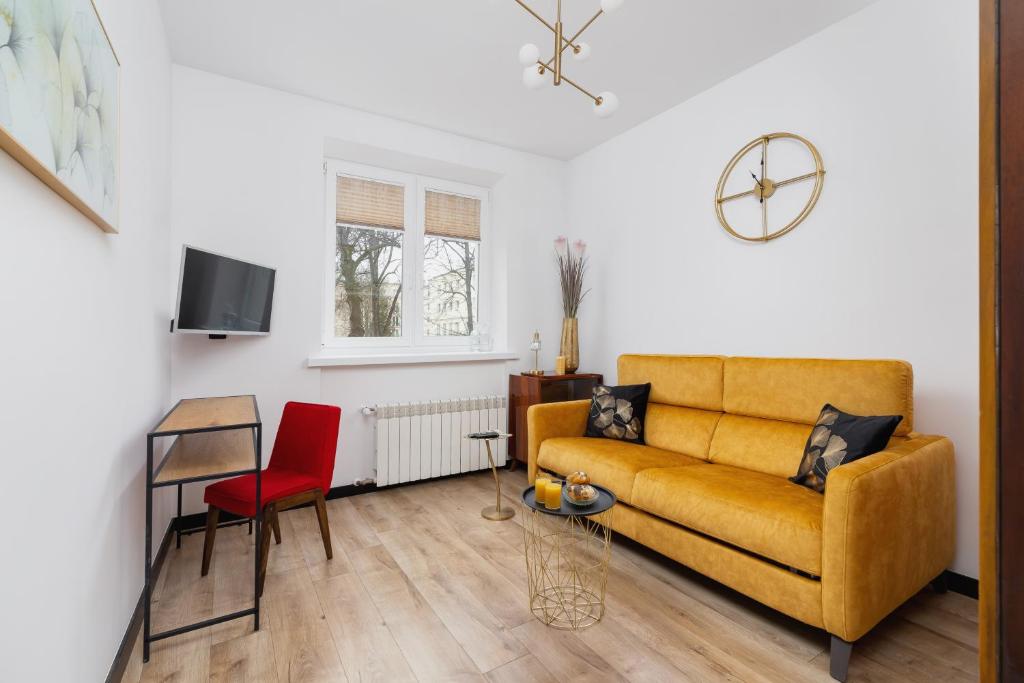 salon z żółtą kanapą i czerwonym krzesłem w obiekcie Apartments Osiedle Szkolne Cracow by Noclegi Renters w Krakowie