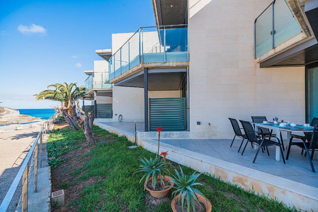a house with a table and chairs and the ocean at Mirador Blue G in Cala de Sant Vicenc