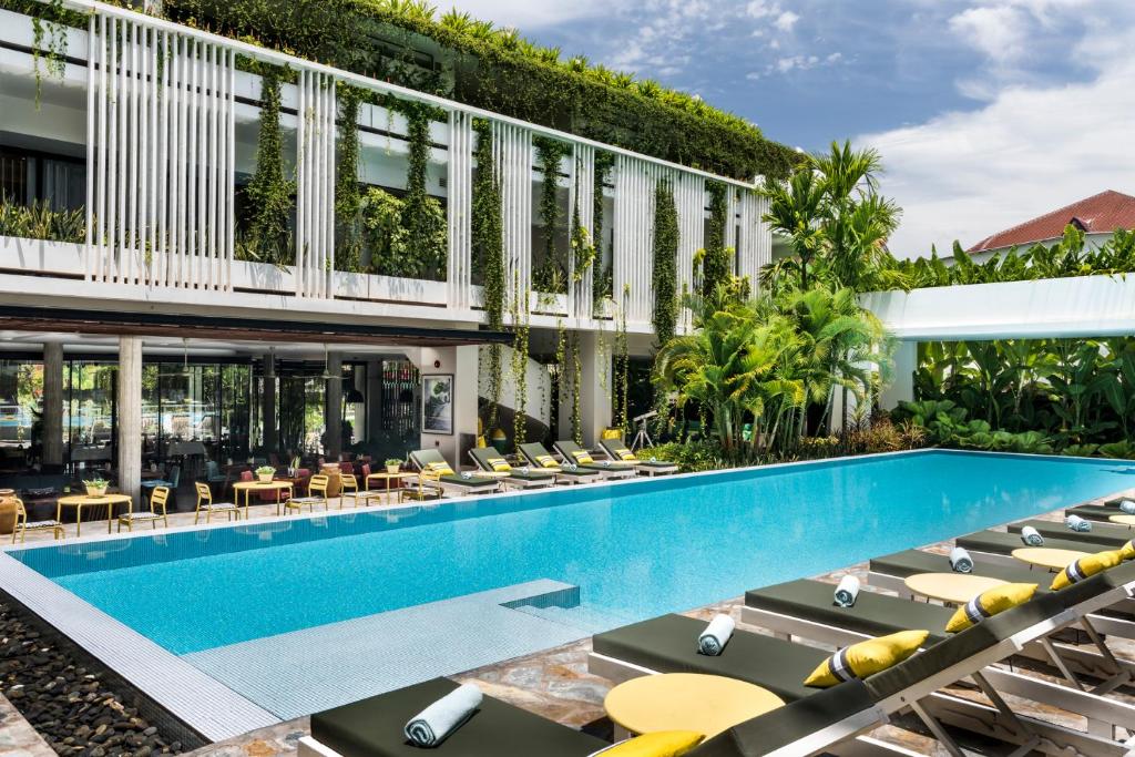 an outdoor swimming pool with lounge chairs and a building at Viroth's Hotel in Siem Reap