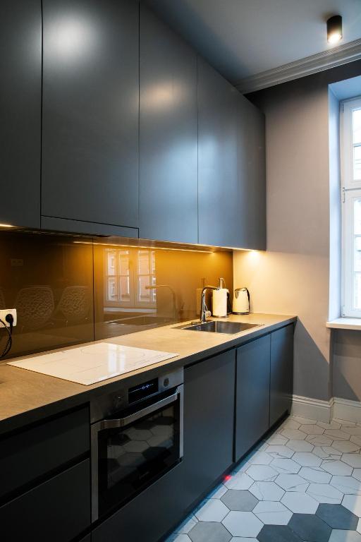 a kitchen with black cabinets and a sink at Maya's Flats & Resorts 44 - 3 rooms apartment on Chlebnicka Street Gdańsk Old Town in Gdańsk