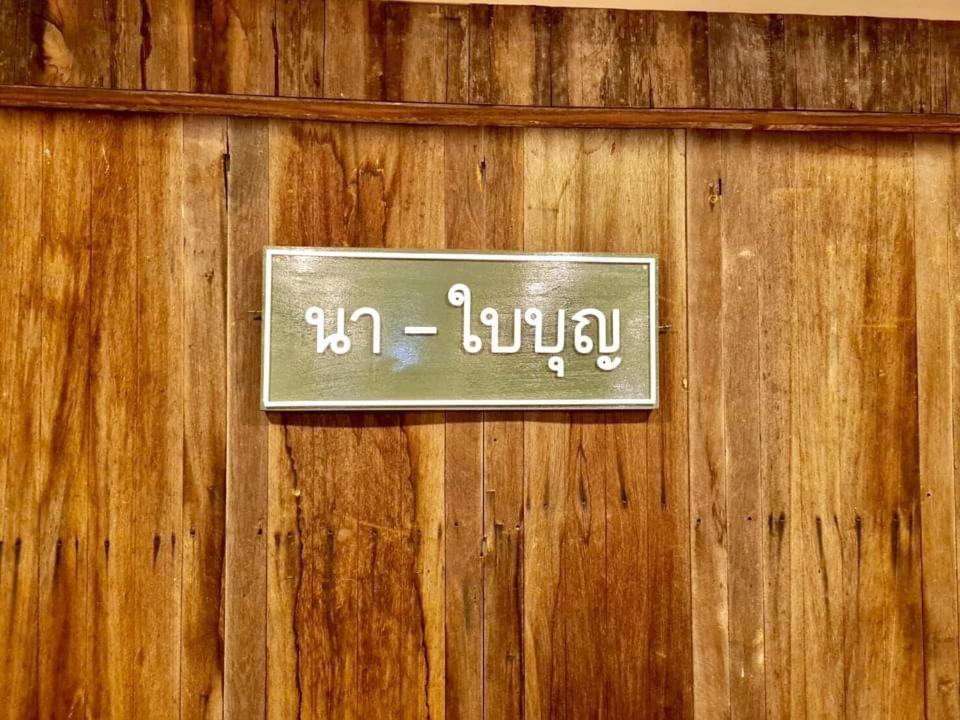 a sign on a wooden wall with writing on it at นา-ใบบุญ Nabaiboon in Chiang Khan