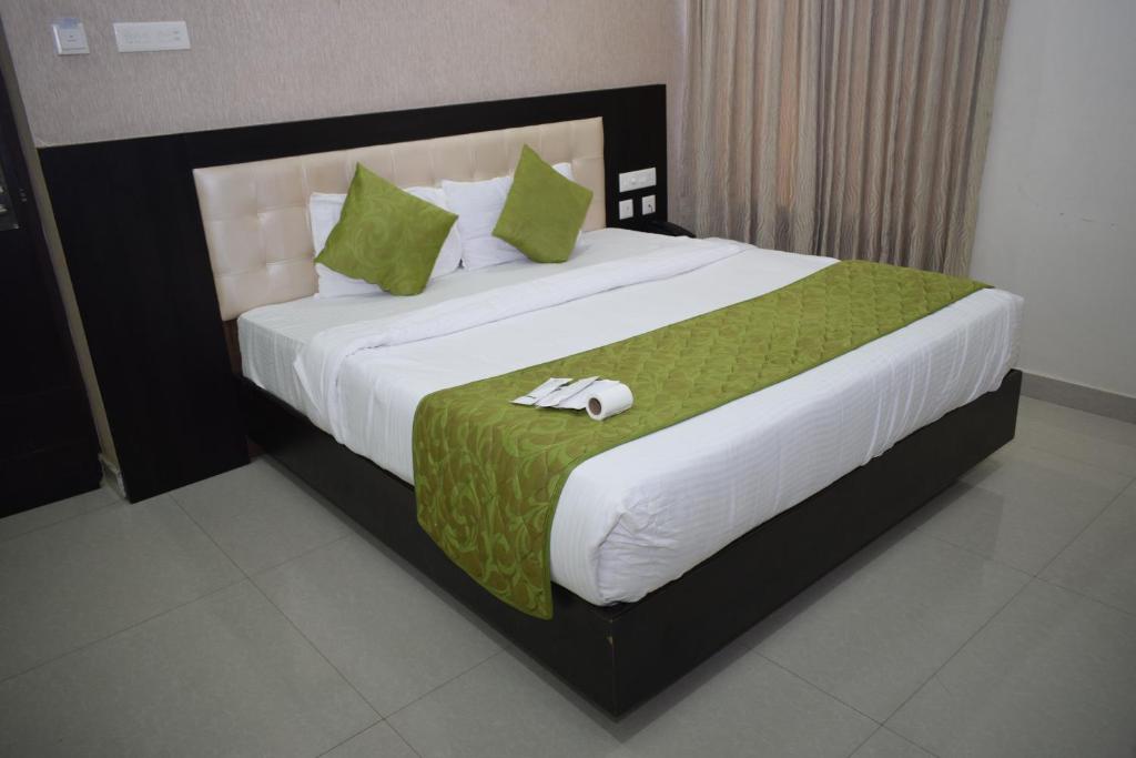 1 dormitorio con 1 cama grande con sábanas verdes y blancas en Shri Subham Residency, en Srīrangam