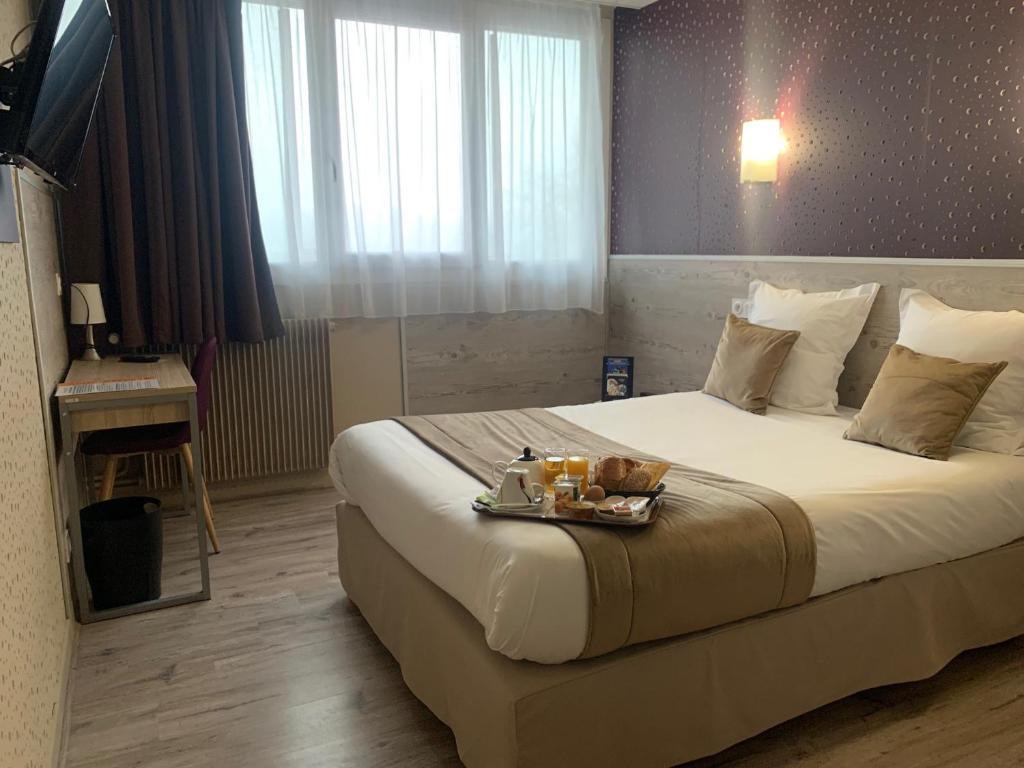 a hotel room with a bed with a tray of food on it at Contact Hôtel Foch in Besançon