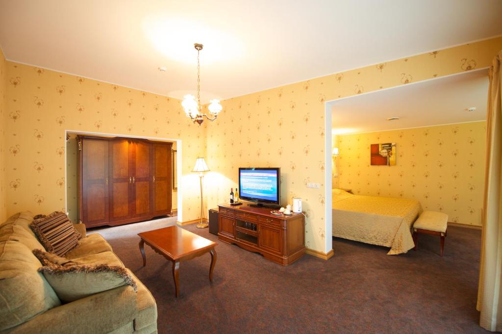 uma sala de estar com um sofá, uma cama e uma televisão em Villa Hotel Theresa em Rakvere
