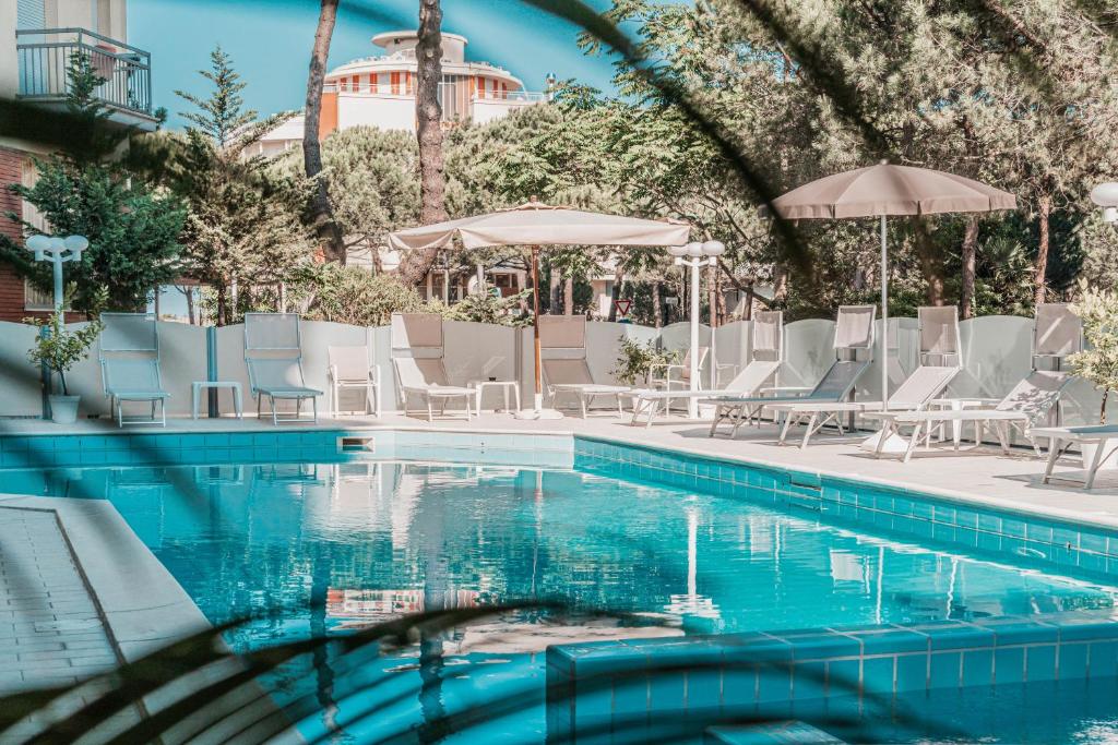 una piscina con sillas y sombrillas blancas en Hotel San Giorgio, en Milano Marittima
