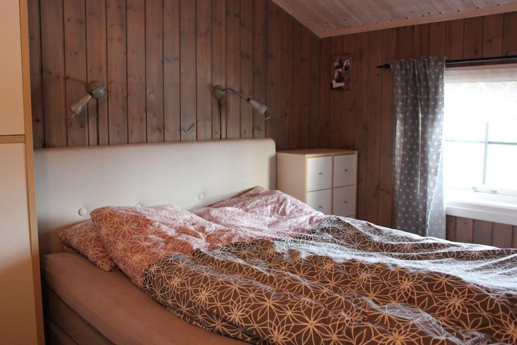 a bedroom with a bed with a comforter on it at Hytte sentralt Ljøsheim, Ringsaker(nær Sjusjøen) in Ringsaker
