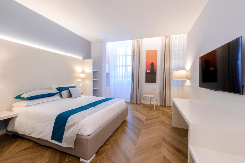 um quarto branco com uma cama e uma televisão em Hotel Baylle em Cagliari