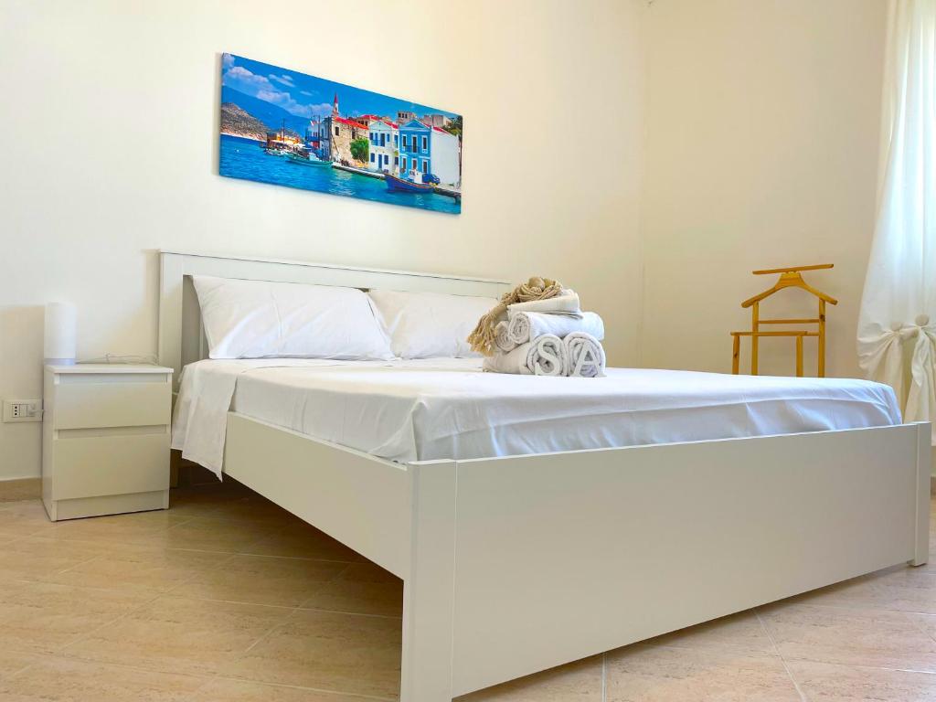 a white bed with a teddy bear sitting on it at Appartamento Indipendente al Mare Sweet Apartments in Santa Marinella